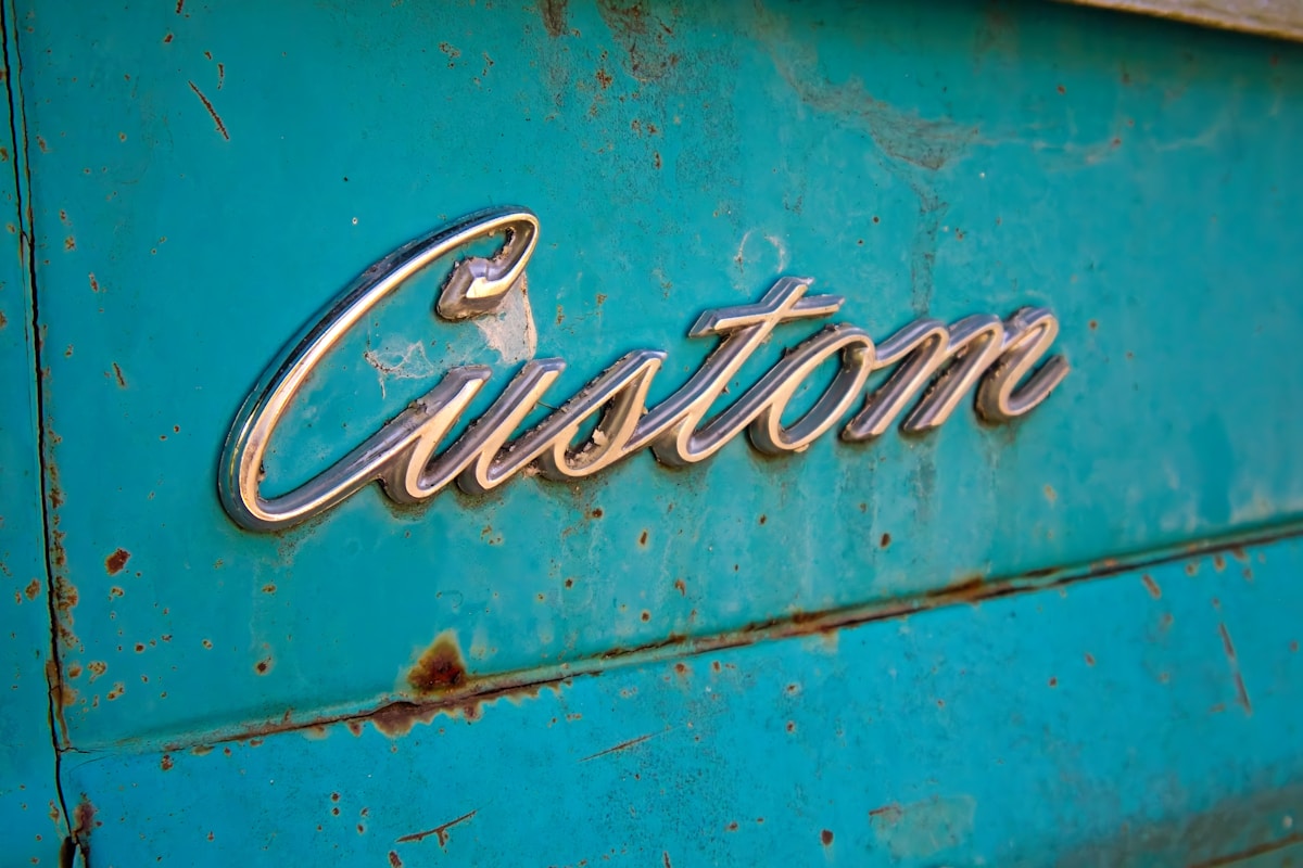 Emblème vintage en métal doré sur une surface turquoise rouillée.