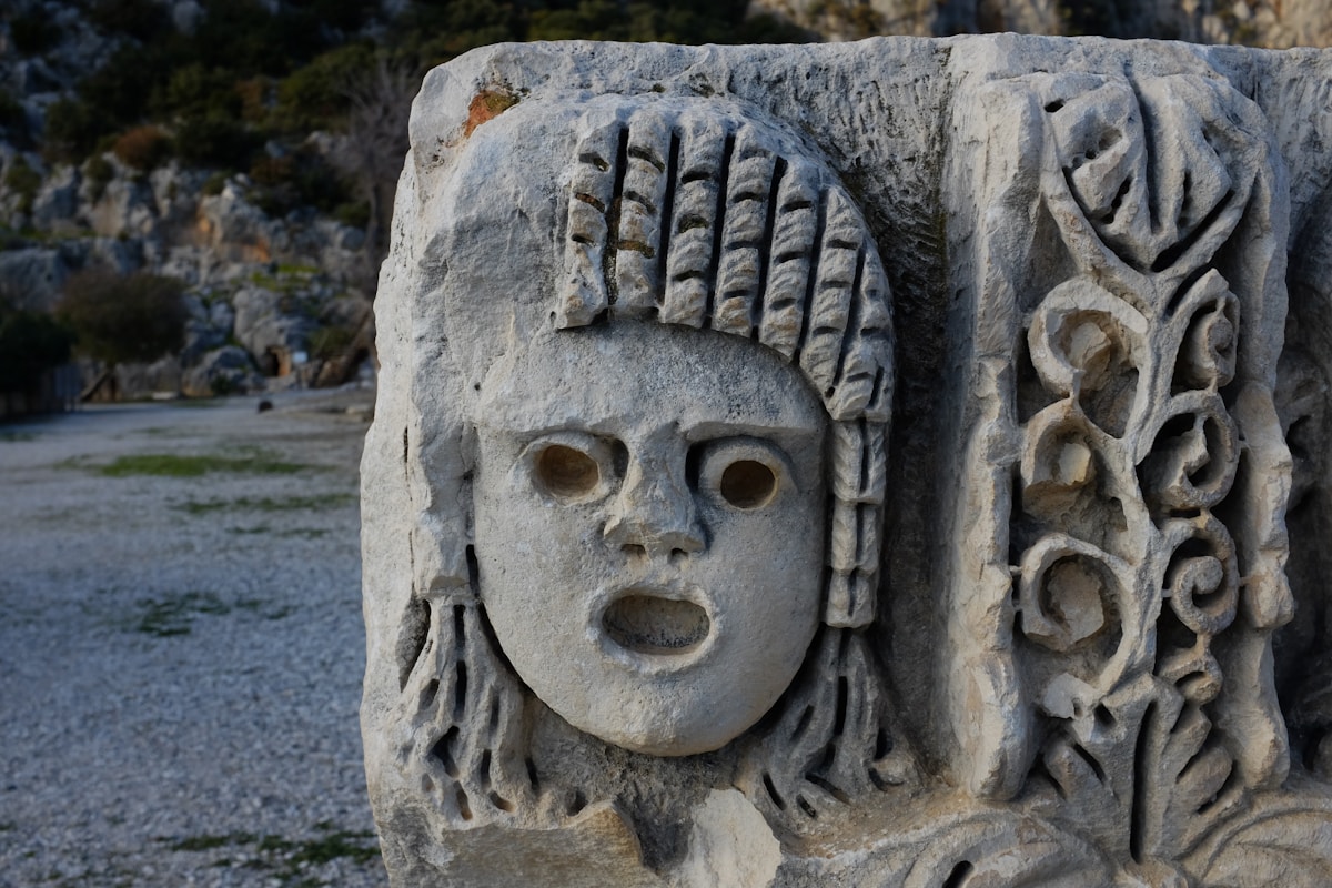 Sculpture de visage féminin antique aux traits stylisés.