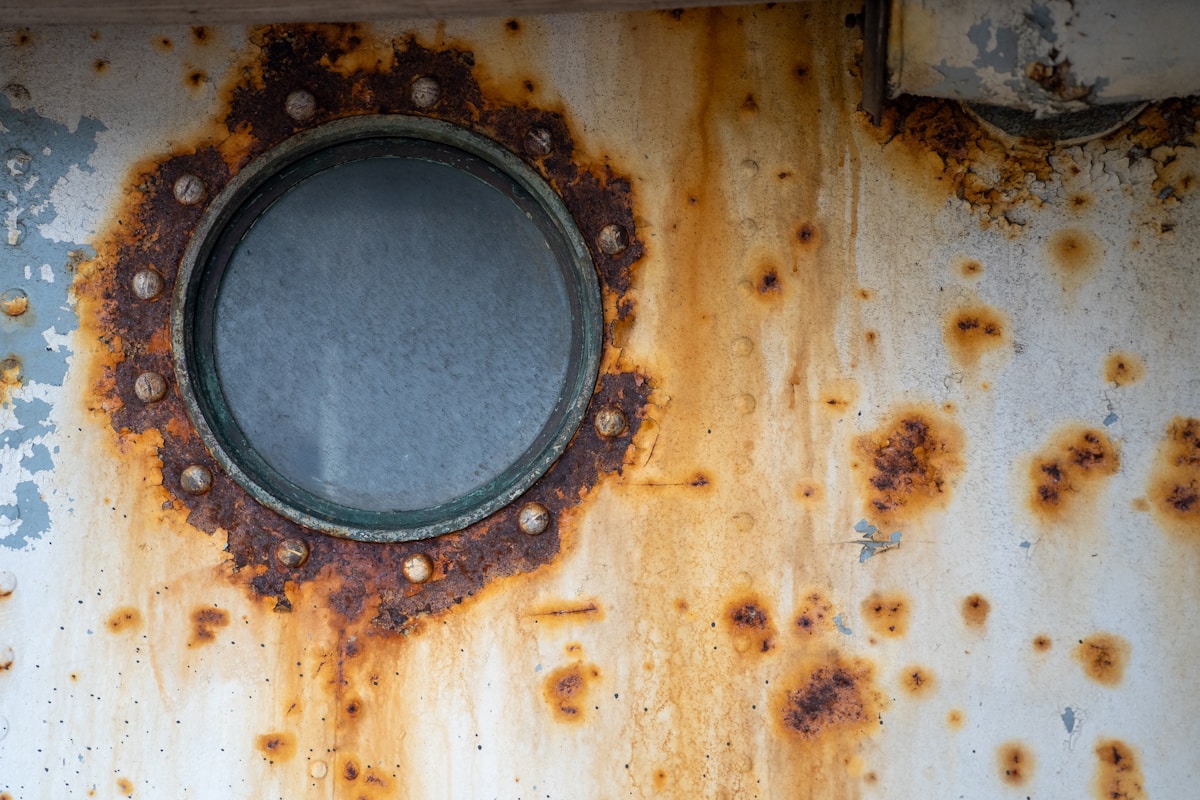 Miroir rond rouillé sur mur délavé et taché.