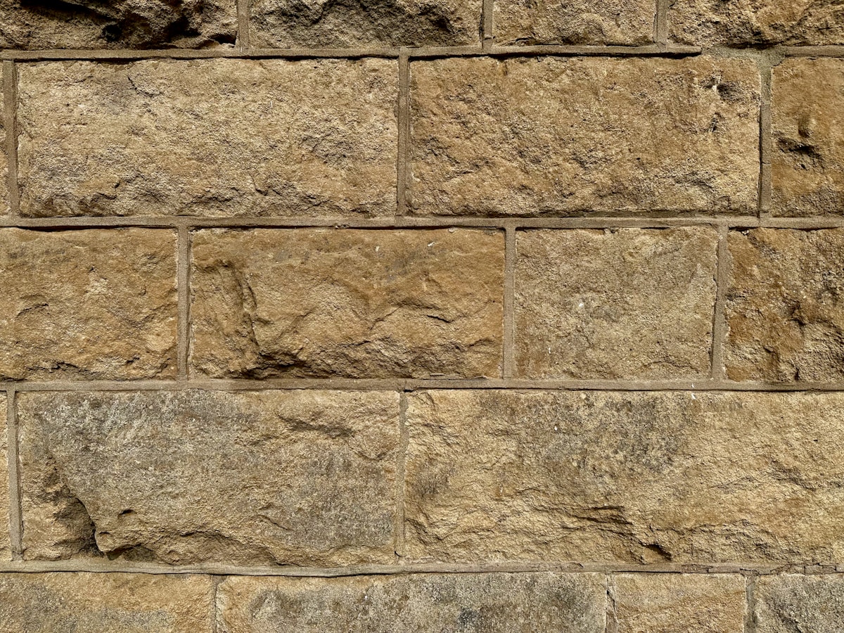 Mur de pierres de taille irrégulières, texturé et vieilli.