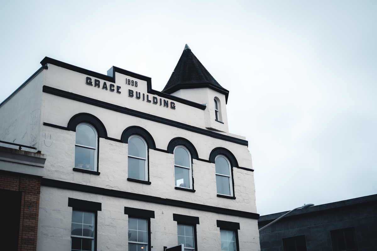 Bâtiment historique en briques blanches avec fenêtres en arc et toit pointu.