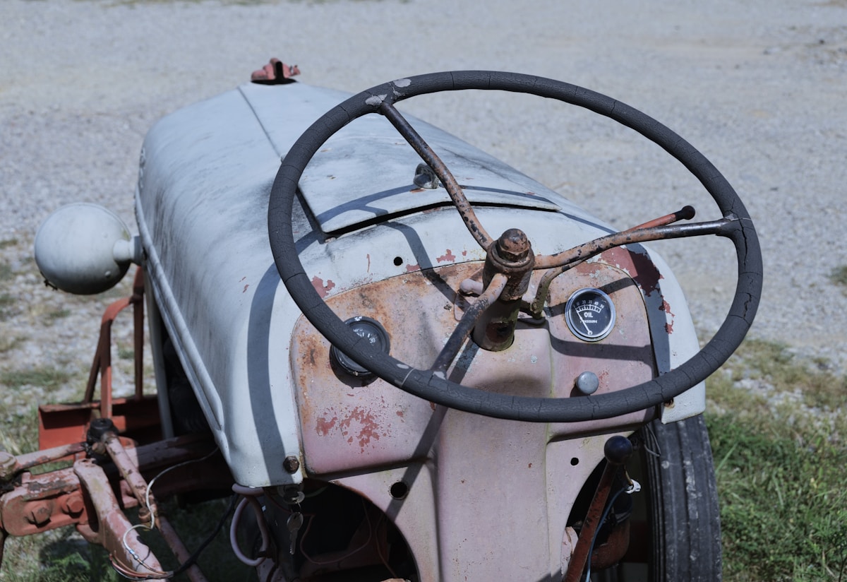 Vieux tracteur agricole rouillé avec volant et tableau de bord.