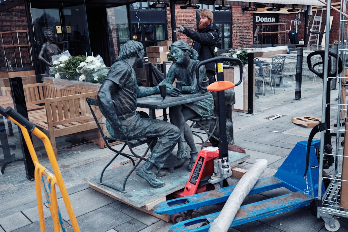 Statues de personnes jouant aux cartes dans un environnement urbain.