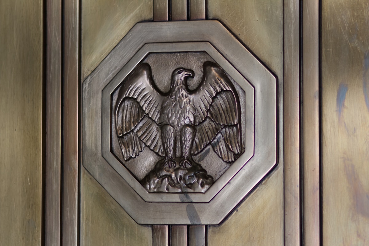 Aigle sculpté en métal sur un panneau de bois.